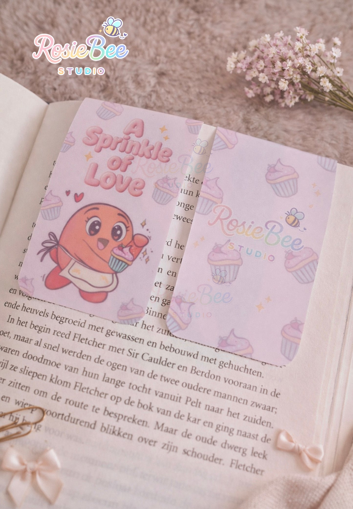 Magnetische boekenlegger “A Sprinkle of Love” met Moji Friend Liefde op een open boek in cosy setting met bloemen en strikjes.