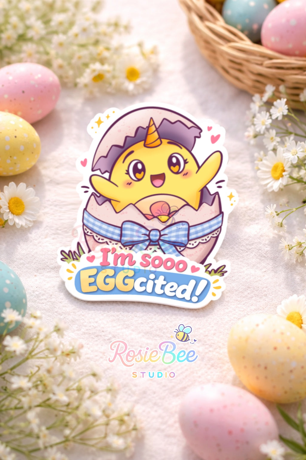 Glossy vinyl sticker van Moji Friend Blijheid die blij uit een ei springt met de quote “I’m sooo EGGcited!”, liggend tussen pastel paaseieren en kleine witte bloemetjes.