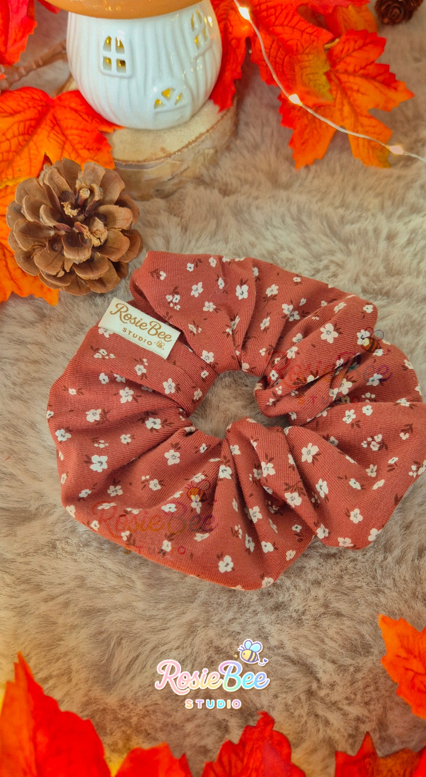 Handgemaakte Soft Ember scrunchie van RosieBee Studio van roestkleurige tricot stof met kleine lichte bloemenprint, ca. 12 cm doorsnee.