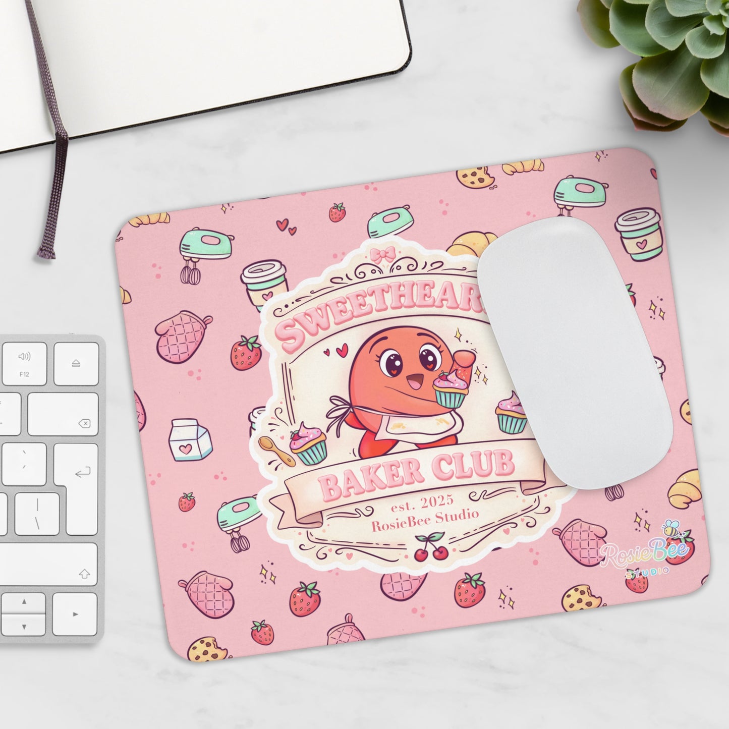 Sweetheart Baker Club pastel bakery muismat met Moji Friend Liefde illustratie op bureau naast toetsenbord en muis.