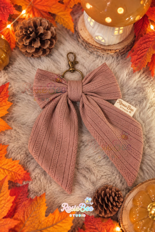 Handgemaakte Autumn Bow sleutelhanger van RosieBee Studio in oudroze stof met opengewerkt patroon en bronskleurige metalen sluiting.