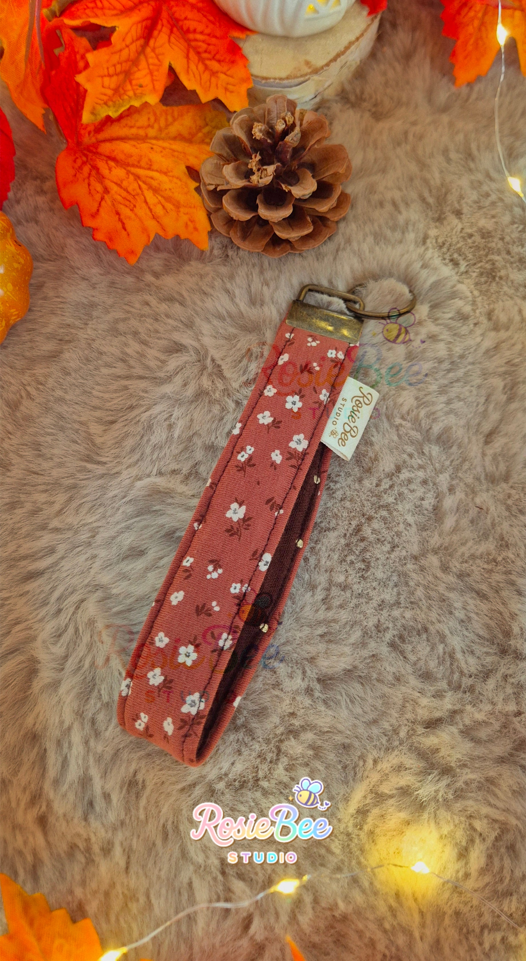 Handgemaakte Falling Ember wristlet van RosieBee Studio met roestkleurige bloemenstof, donkerbruine stof met gouden details en bronskleurige hardware.