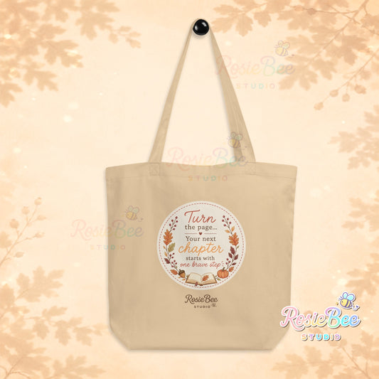 Naturelkleurige A New Chapter tote bag van biologisch katoen met Turn the Page quote, herfstbladeren en open boek van RosieBee Studio.